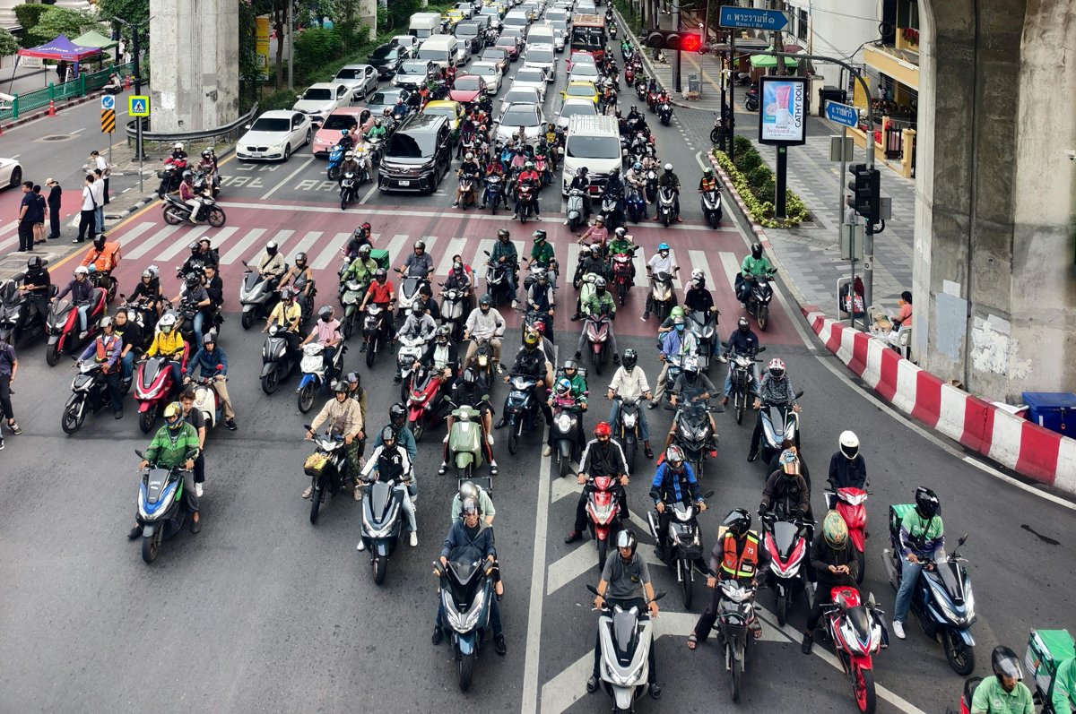 A lot of motorbikes stopped at a traffic light