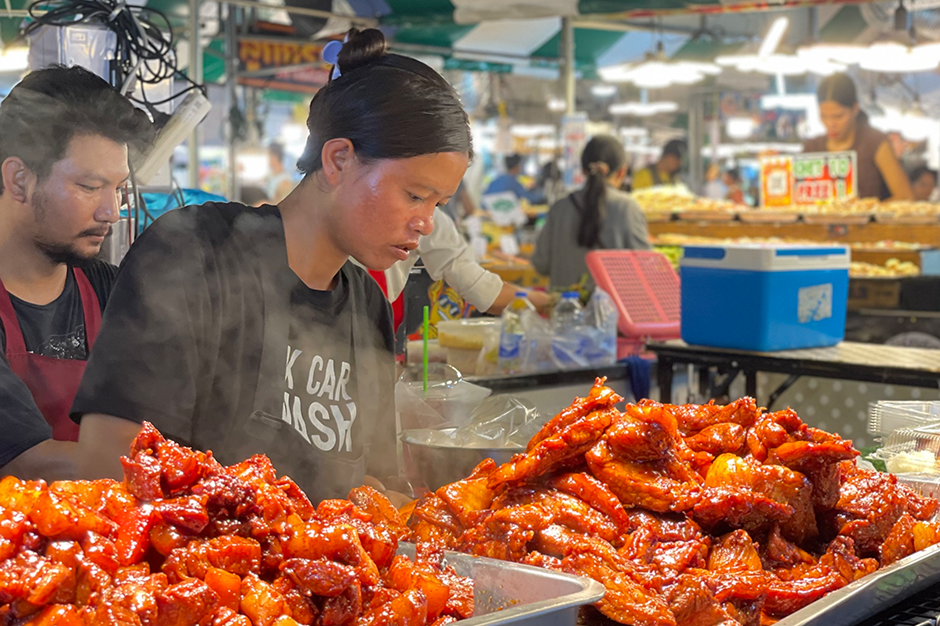 woman grilling chicken at bangkok market
