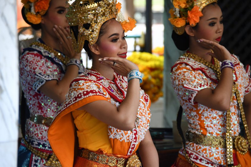 women in thai traditional outfits dancing at erawan shrine.
